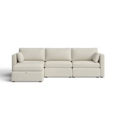 a white sectional couch with pillows on the top and bottom, in front of a white background