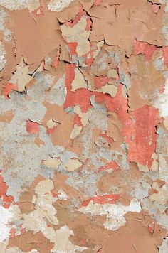 peeling paint on the side of a wall with red and white streaks in it's center