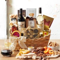 a wine and cheese gift basket with two glasses of wine, nuts and crackers