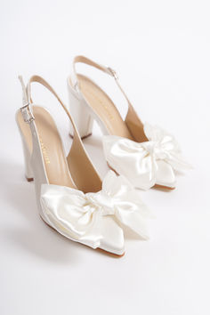 two white shoes with bows on the toes and one has a heel in the shape of a shoe