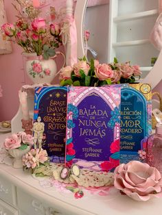 a table topped with books and flowers next to a mirror