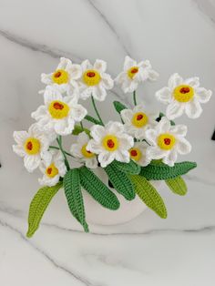 crocheted flowers in a white vase on a marble surface