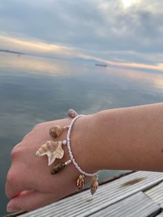 Handmade seashell charm bracelet. Made with ethically handpicked seashells, beads and stainless steel parts. The bracelet is made on request, which means the shell charms can differ from the shells in the pictures. The center piece shell (pelicans foot shell) will stay the same. For example look at the two different bracelets in the picture. It's also possible to choose your own shells, or to add beads or pearls to the charms. Just send me a message! Seashell Bracelet Ideas, Sea Shell Bracelet Diy, Things To Make With Shells, Seashells Bracelet, Shell Jewelry Ideas, Seashell Pictures, Bracelet With Shells, Ocean-inspired Shell Bracelets As Gift, Ocean-inspired Shell Beaded Bracelet