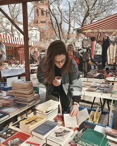 a woman standing over a table filled with books