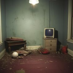 an old tv sitting on top of a dresser in a room with blue walls and peeling paint