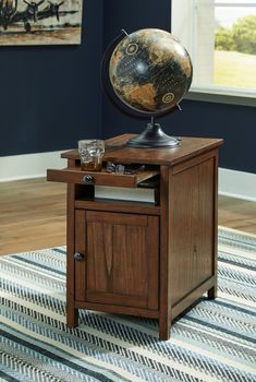 a wooden table with a globe on top and a glass in the drawer below it