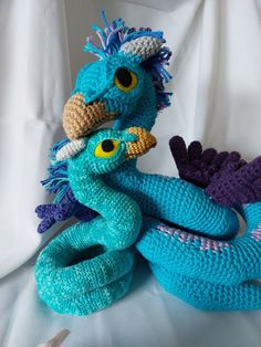 two crocheted stuffed animals sitting next to each other on a white surface,