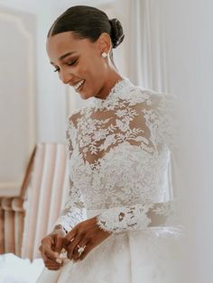 a woman in a white wedding dress standing next to a bed