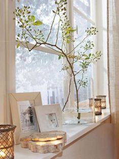 a window sill with candles and pictures on it, next to a tree branch