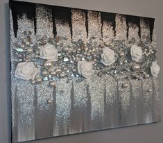 a painting with silver glitter and white roses on the bottom, in front of a gray wall