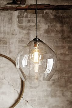 a light bulb hanging from the ceiling in front of a concrete wall with a circular object on it