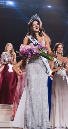 a woman in a silver dress is holding flowers and posing for the camera with other women