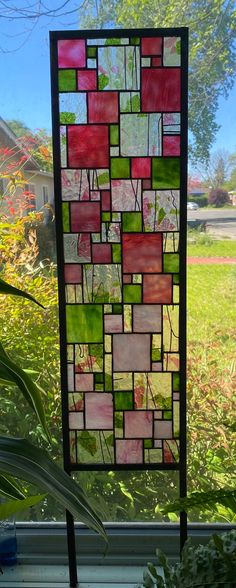 a stained glass window sitting on top of a wooden table next to a potted plant