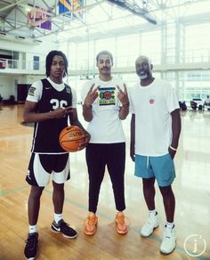 three men standing next to each other on a basketball court