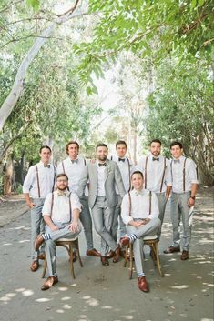 a group of men standing next to each other in front of some green trees and bushes