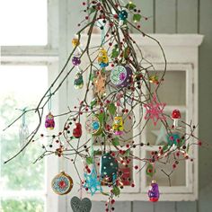 a christmas tree with ornaments hanging from it's branches in front of a window