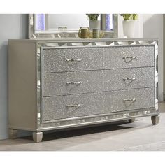 a silver dresser with two mirrors on top of it