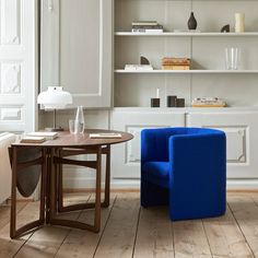 a blue chair sitting next to a table on top of a hard wood floored floor