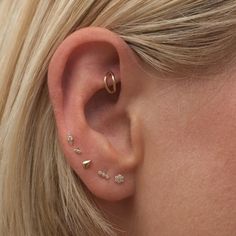 a close up of a woman's ear with three different types of piercings