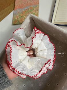 a hand holding a white and red paper flower in it's left hand, next to an open book