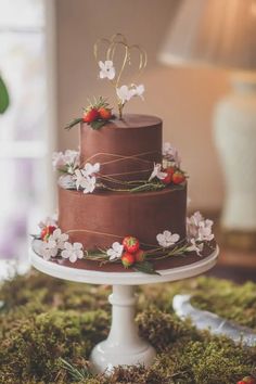 a three tiered chocolate cake with flowers on top