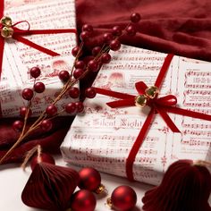 two wrapped presents with red ribbons and bows on them sitting next to some christmas decorations