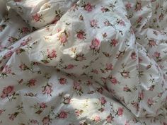 an unmade bed with pink roses on it