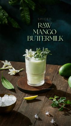 a wooden table topped with a glass filled with green liquid and lime wedges next to it