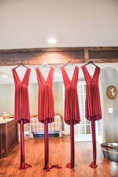 three red dresses hanging in the middle of a room