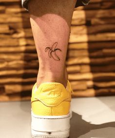 a person's foot with a banana tattoo on their left leg and yellow sneakers