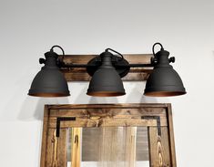 three light bathroom vanity fixture with mirror in the corner and wood frame around it, hanging from wall