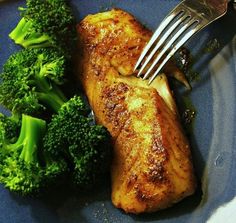 a blue plate topped with meat and broccoli next to a knife and fork