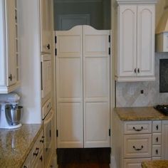 a kitchen with white cabinets and marble counter tops