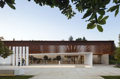 the entrance to a modern house with wooden slats on it's sides and people walking outside