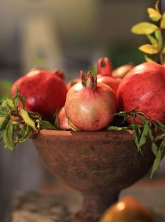 a bowl filled with lots of pomegranates on top of a table