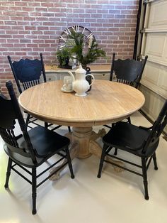 a wooden table with four chairs around it and a brick wall in the back ground