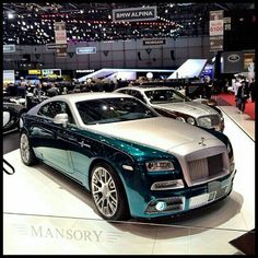 two rolls royces are on display at an auto show, one is blue and the other is white