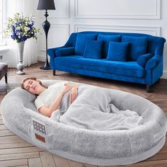 a woman laying on top of a dog bed in a living room