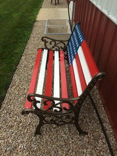 a bench with an american flag painted on it sitting in front of a red, white and blue building