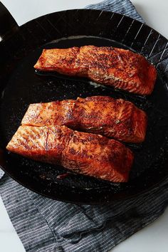 two salmons cooking in a skillet on a table