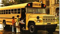 two children are standing in front of a school bus that is parked on the street