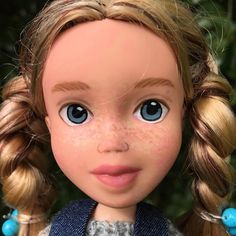 a close up of a doll with blue eyes and blonde hair, wearing a sweater