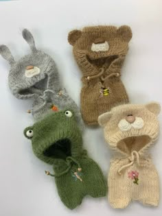 four knitted animal mittens sitting next to each other on a white table top