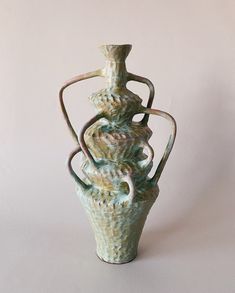 a ceramic vase sitting on top of a white table next to a pink wall and floor