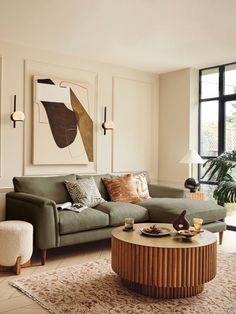 a living room filled with furniture next to a large window and a painting on the wall