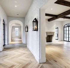 an empty living room with wood floors and white brick walls, along with two fireplaces