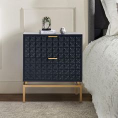 a nightstand with two birds on it next to a bed