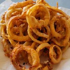 a pile of onion rings sitting on top of a white plate