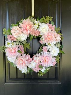 a wreath with pink and white flowers hanging on a door