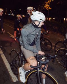 a man riding a bike down a street at night with other bicyclists